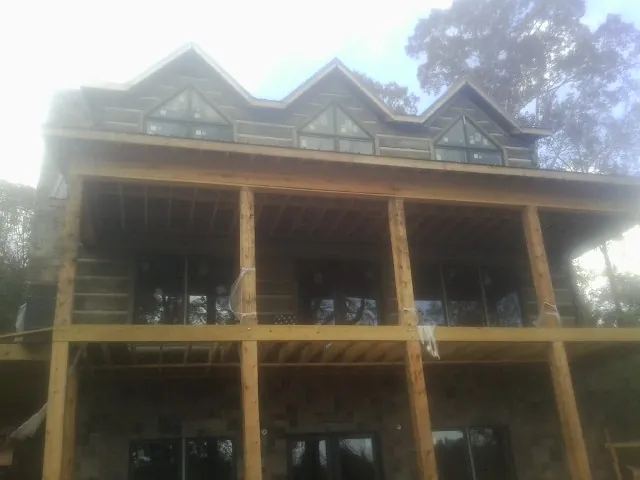 Dormers and porch framing on a large log home under construction — Roof Coating work by our crew in Burlingham