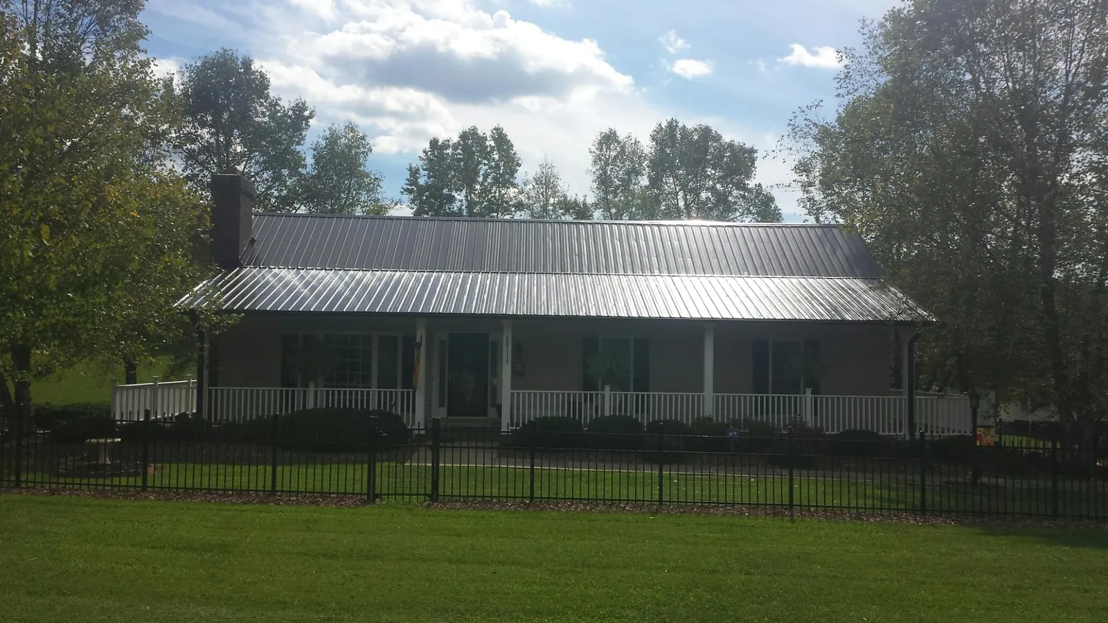 Gray metal roof on a brick ranch with a full width front porch — Gutter Guard Installation work by our crew in Burlingham